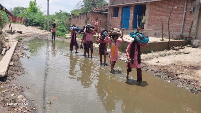 हाथ में जूते पकड़ कीचड़ से होकर स्कूल जाने को मजबूर स्कूली बच्चे